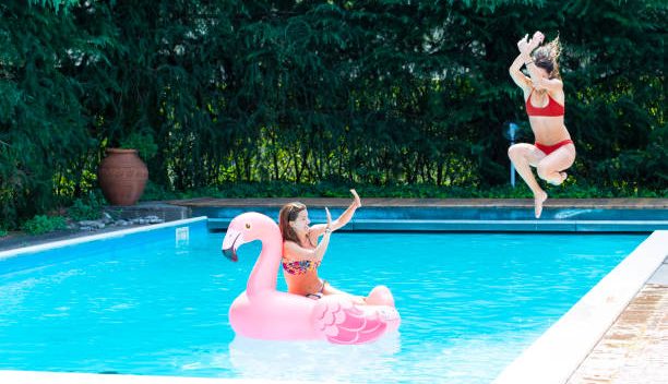 Une maman et sa fille qui s'amusent dans la piscine de leur jardin